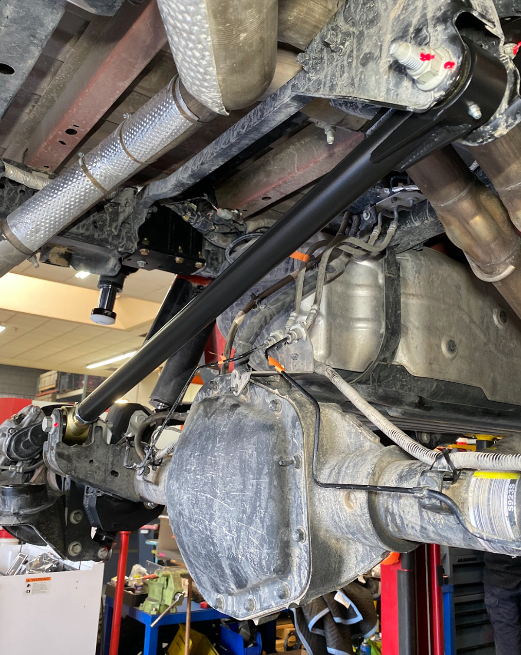 Angled underside view of a Gen 3 Raptor showing the adjustable panhard bar routed past the exhaust