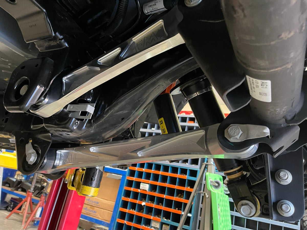 Raw billet upper rear arm at the axle bracket beside the rear shock on a Bronco Raptor