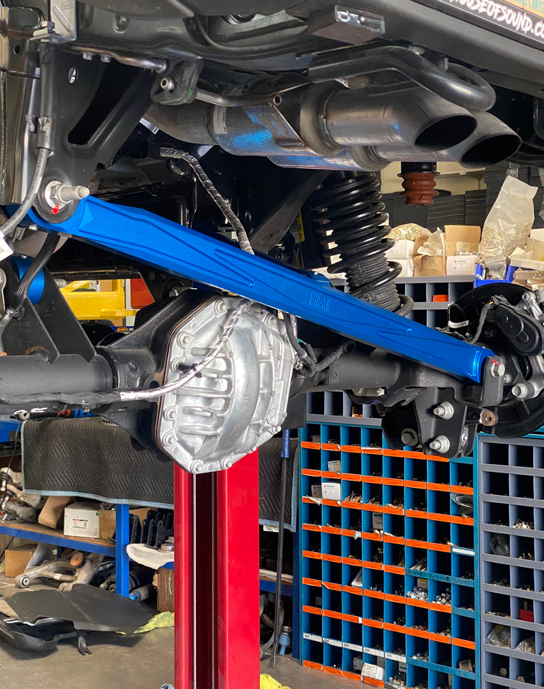 Blue anodized billet panhard bar beside the rear shock on a Bronco Raptor on the lift