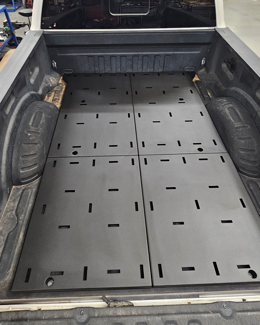 Full-length Super Duty bed deck showing the four bolt-together deck plates in textured Hammer Black powder coat