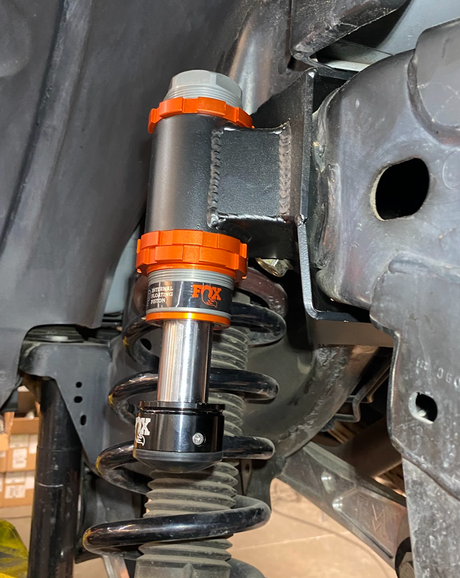 Adjustable bump stop with orange anodized body installed above a coilover in a Ford Bronco wheel well