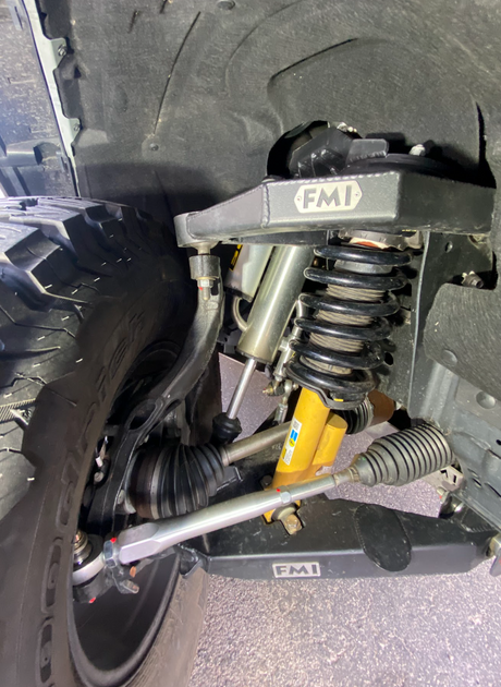Ford Bronco front suspension close-up showing a Foutz Motorsports fabricated upper control arm and coilover shock