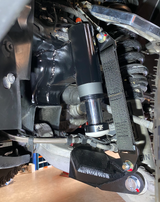drivers side of Stock lower arm Front Limit Strap with Bump Stop Stock installed on a ram TRX 