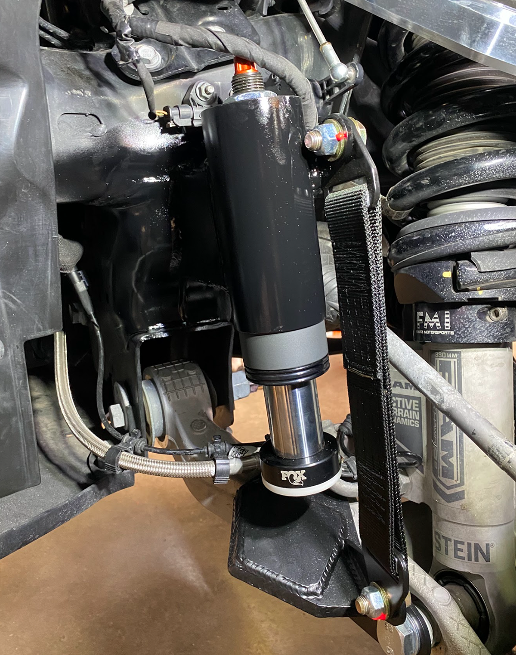 suspension upgrade close of a 2025 Ram RHO with a Front Limit Strap & Bump Stop installed on a Stock Lower Arm