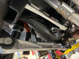 Close view of a raw billet lower arm and uniball under a Bronco Raptor with the shock in frame