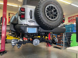 Rear three-quarter view of a Ford Bronco Raptor on the lift with the rear suspension exposed