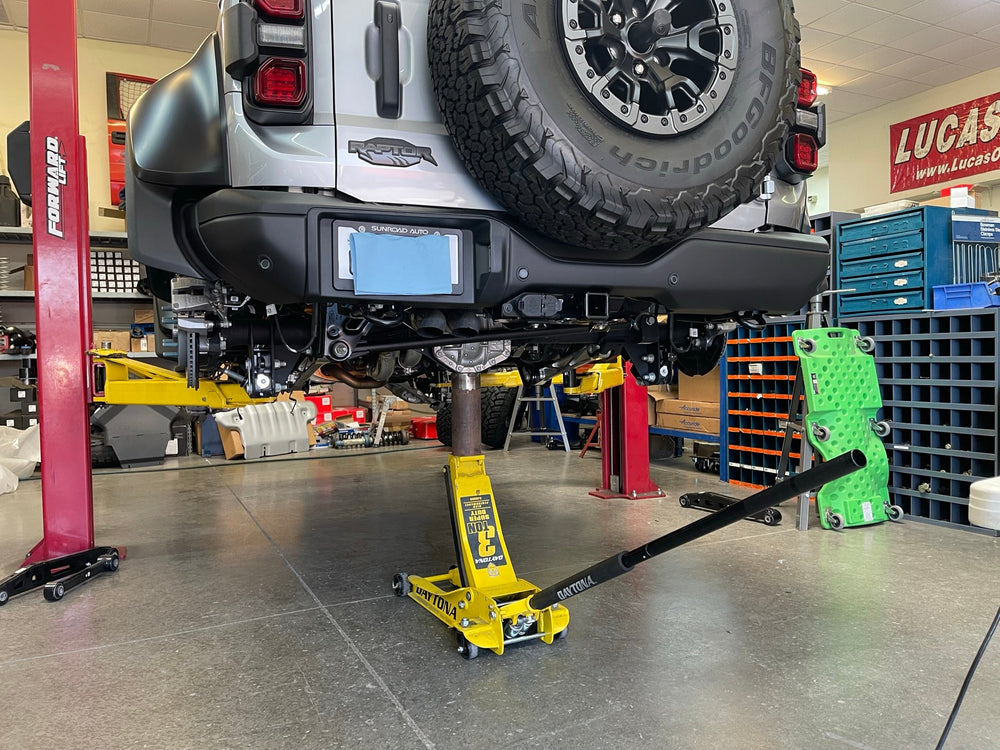 Bronco Raptor on the shop lift with a floor jack under the rear axle during installation