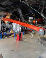 FOX orange anodized panhard bar across a Bronco Raptor rear axle on the shop lift