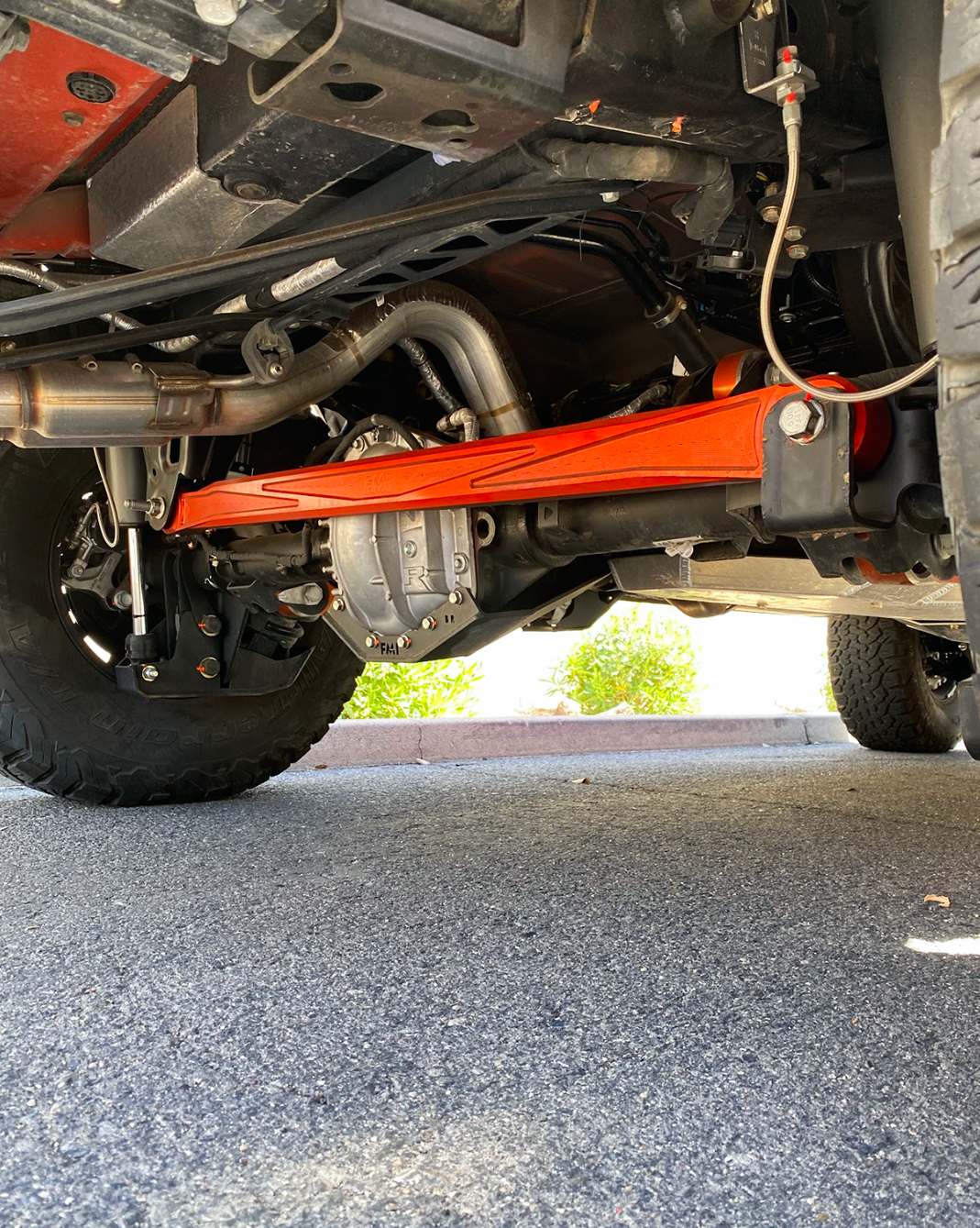 FOX orange anodized billet panhard bar under a Bronco Raptor parked on gravel