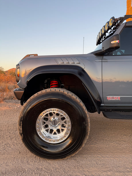 Front corner of a Ford Bronco Raptor on Geiser Off-Road progressive springs, coil spring visible behind the wheel