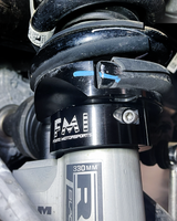 Detail of a black anodized FMI leveling collar seated under the factory front coil spring on a Ram RHO