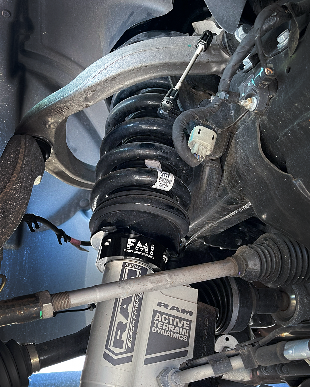 Adjustable ride height sensor connector rod and black anodized 2.5" lift collar installed on the 2027 Ram TRX front suspension